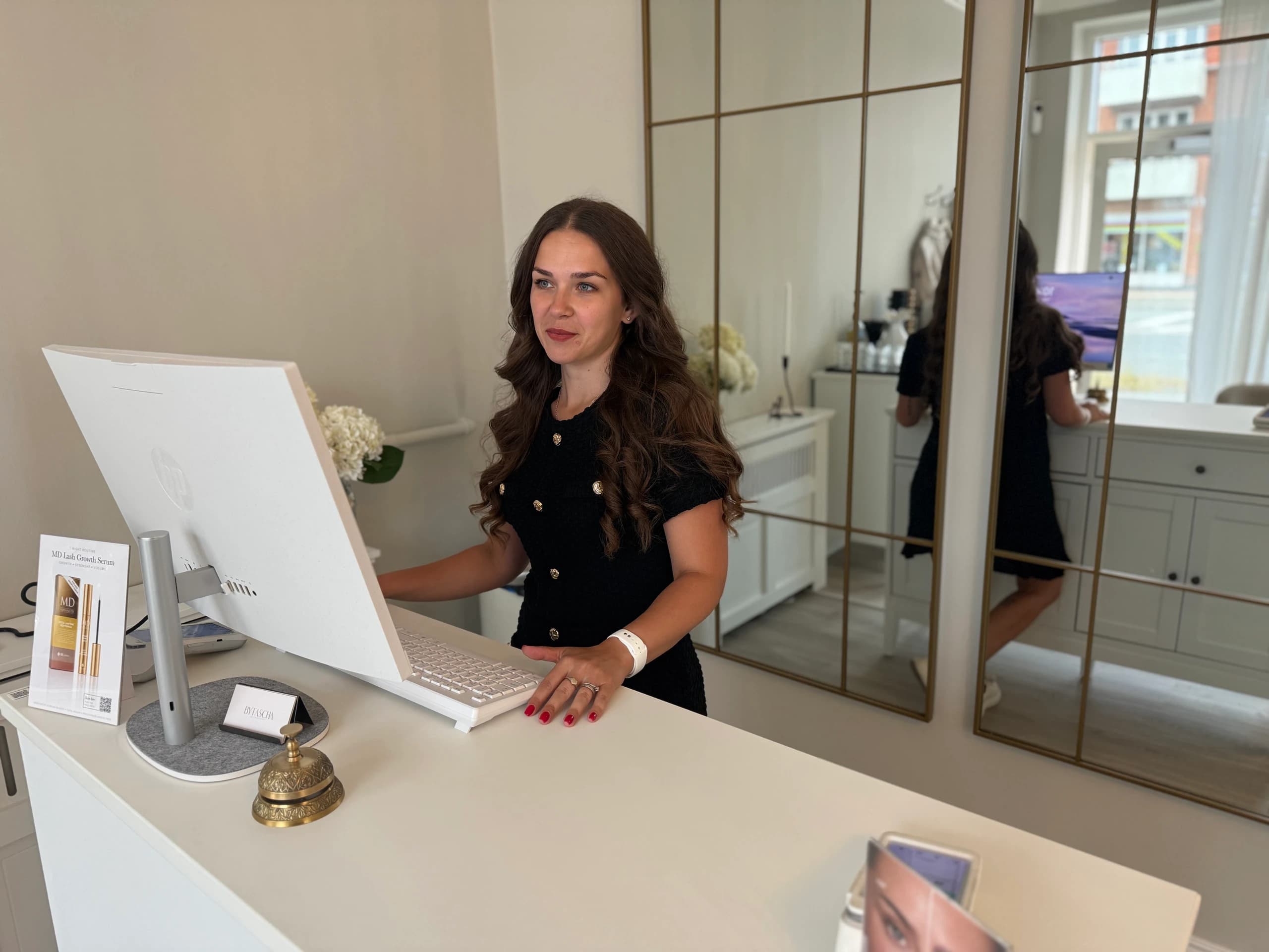 Beauty Hour-terapeut byder en gæst velkommen ved receptionen i blødt dagslys