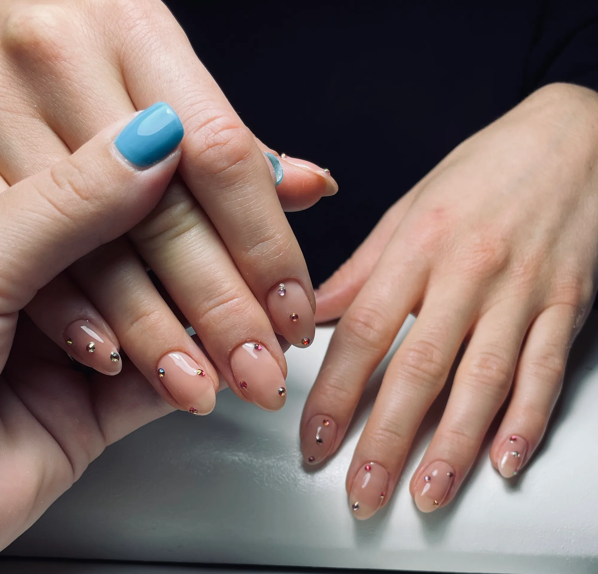 Nude gelemanicure med spredte krystaldetaljer og en himmelblå accentnegl - Beauty Hour Hellerup